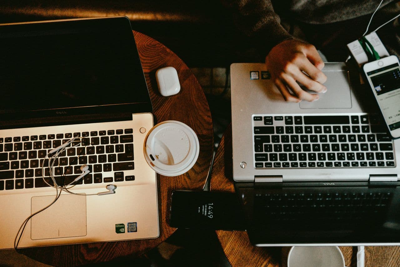 Person using a laptop on brown wooden table.