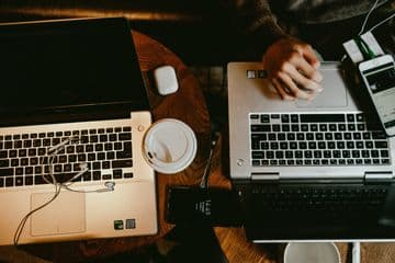 Person using a laptop on brown wooden table.