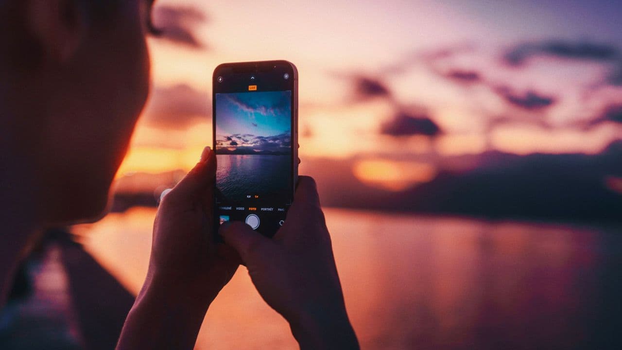 A woman taking a picture of a sunset with her mobile phone - Photo by Jerry Kavan on Unsplash A woman taking a picture of a sunset with her mobile phone - Photo by Jerry Kavan on Unsplash